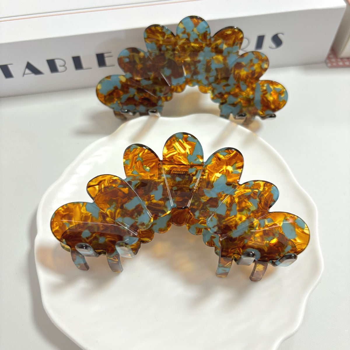 Petal large grip hair accessories displayed on a plate, featuring elegant petal clip design in orange and blue.