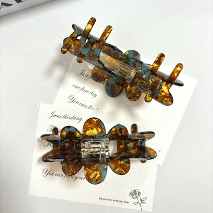 Petal large grip hair accessories in tortoiseshell design on a background with motivational quotes.